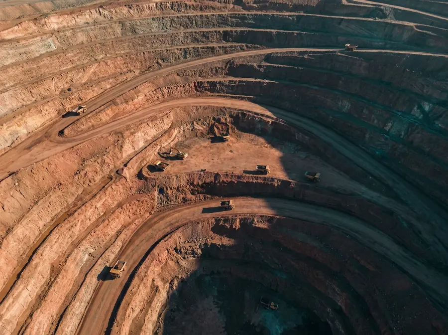 Aerial view of the terraced benches of an open-pit mine with haul trucks